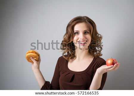 Young woman with hamburger and apple