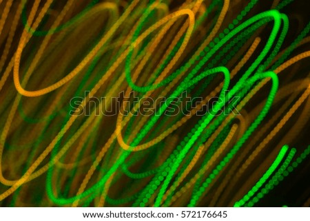 Blurred moving diagonal LED lights, festive abstract color background. Green and orange.