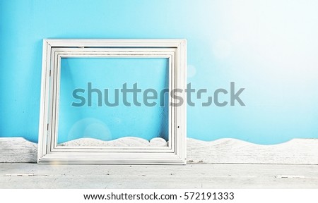 Vintage picture frame on white wooden table in front of blue background. Memory Concept.