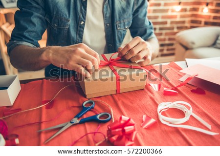Cropped image of handsome romantic guy making present for his better half