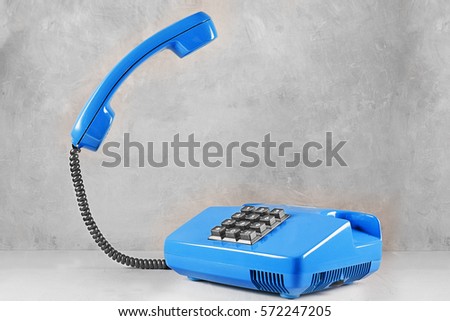 landline blue phone on a gray wall background