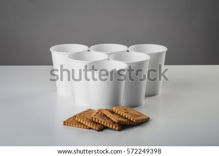 Some white cup with biscuit on gray table