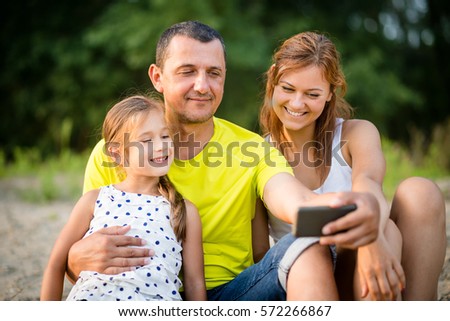 Summer scene of a father with daughters taking selfie with his smartphone