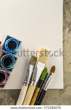  Paint brushes, acrylic paint on white paper for drawing. Place for the inscription. Flat lay