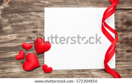 Greeting card with red hearts and ribbon on a old wooden background