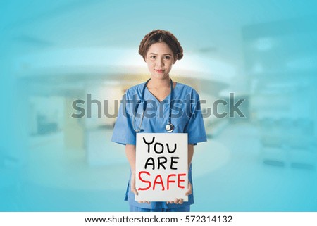 Young Female Asian nurse holding a white board sign with blurred medical background, for communication, health care, medication, technology, health insurance, safety, AEC, medical career concepts