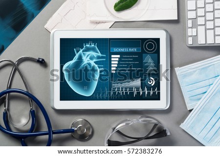 White tablet pc and doctor tools on gray surface Royalty-Free Stock Photo #572383276