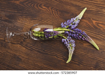 Wineglass with puffy violet lupins on the wooden background