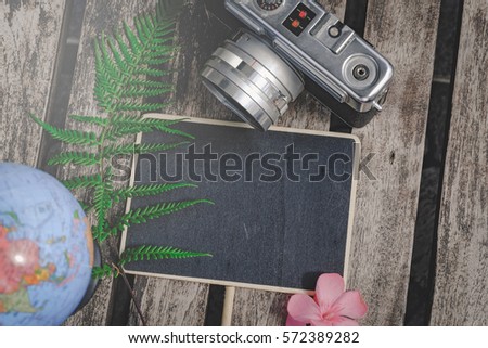 top view flat lay blank wooden signage, globe and vintage camera on wooden table and green fern leaf