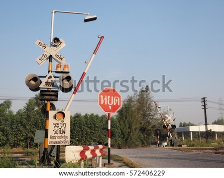 Traffic light and stop post at railroad crossing in Thailand.