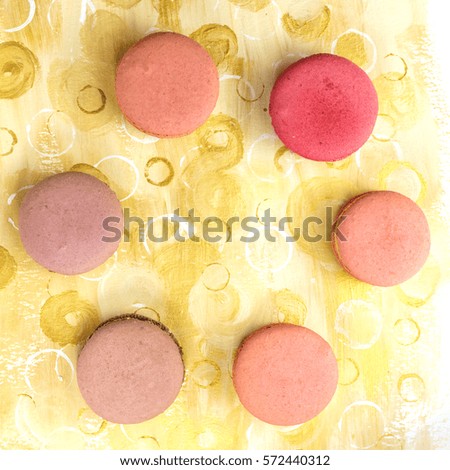 A photo of vibrant macarons, shot from above on a bright yellow background texture, forming a frame for copy space