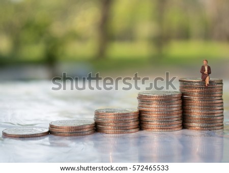 Miniature people: small figures worker siting on top of coins. Money, Financial, Business Growth concept.