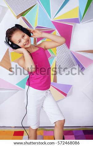 Funny child girl in headphones sings and dances. The concept of music and childhood.