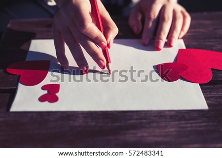 Dos cors royalty free images.Woman writes love letter on white paper with red heart shape figures.Hand made postcard for Saint Valentines Day celebration.Send love letter on 14th of February
