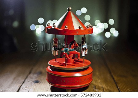 Red carousel toy with blur lights background. Grain and selective focus.