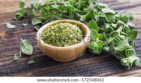 Fresh and dried oregano herb on wooden background Royalty-Free Stock Photo #572548042