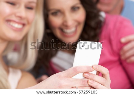 Two Girlfriends Looking At Pictures On phone At Home
