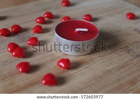 Perfect Saint-Valentine environment. Candies and candle on a wood board. Bunch of red cinnamon heart.