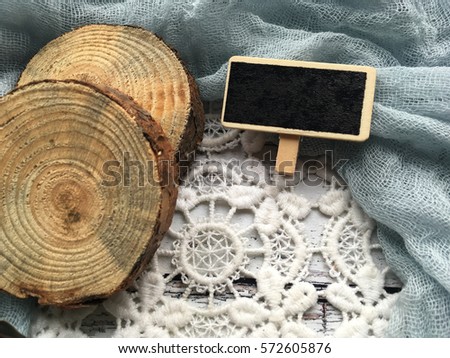 Empty rustic chalkboard on lace with wooden slices. Small chalkboard on grey rustic textile background.