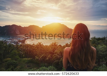 A girl admiring amazing sunset on Phi Phi island. View from the back.
