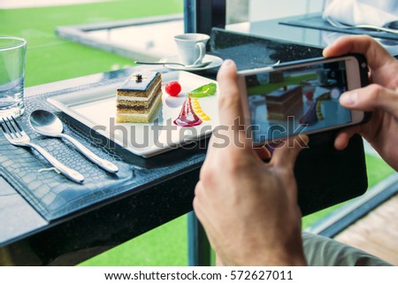 Side view of a man taking a photo of his food in the restaurant. Horizontal indoors shot.