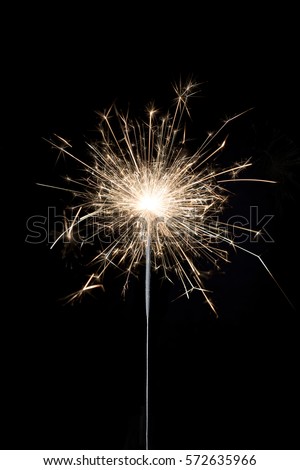 A burning sparkler on a black background Royalty-Free Stock Photo #572635966