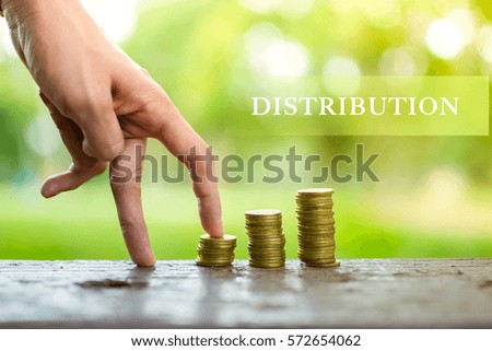 DISTRIBUTION word and hand walking on a pile of coins with blurry background.