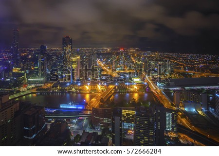 An aerial view of Melbourne cityscape including Yarra River and Victoria Harbour in the distance during cloudy night.