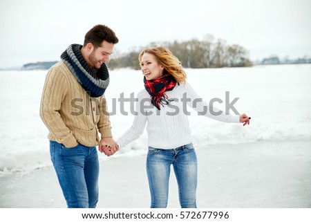 loving couple in warm sweaters skates on a frozen lake