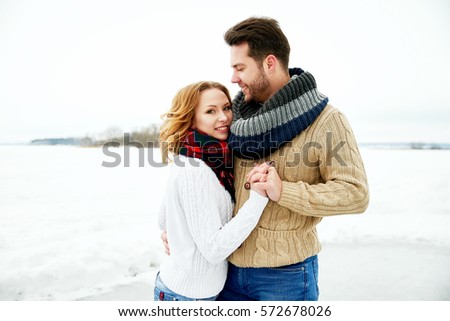 loving couple in warm sweaters skates on a frozen lake