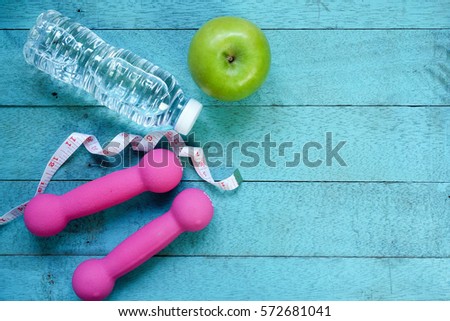 Fitness equipment. Healthy food, water,apple on turquoise wooden background