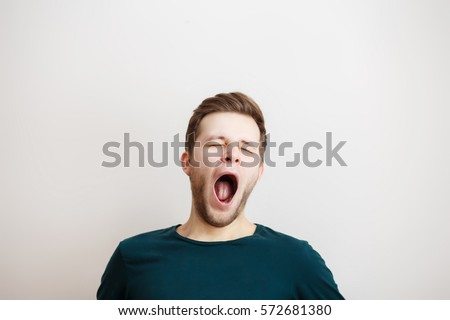 Portrait of yawning man  on a light background Royalty-Free Stock Photo #572681380
