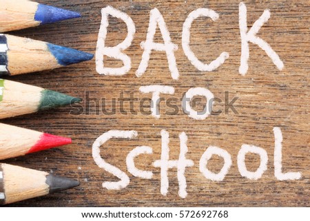 Back To School words on wooden background with part of color pencil tips shown in the frame. Concept of back to school, preparation,routine.