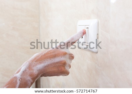 Wet hand of children trun on electric switch. Concept of do not use electricity with wet hand and safety of children. Royalty-Free Stock Photo #572714767