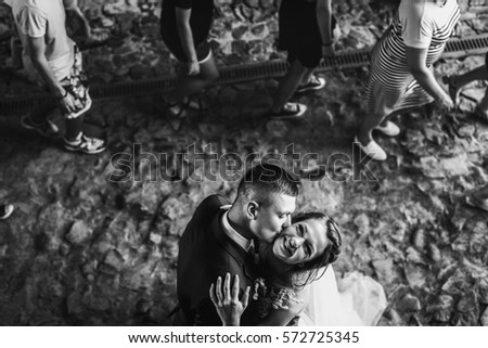 Black and white picture of bride smiling while groom kisses her cheek