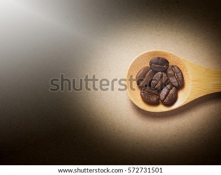 Coffee crop beans on  bamboo spoon and paper texture background