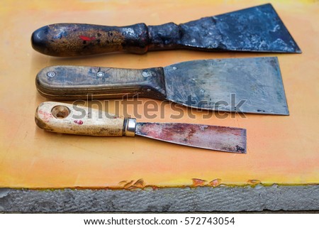 Aged putty knife. decorator, letterpress accessories. Handyman service conceptual image. Knife texture and paint, orange stone plate background. Shallow depth of field.