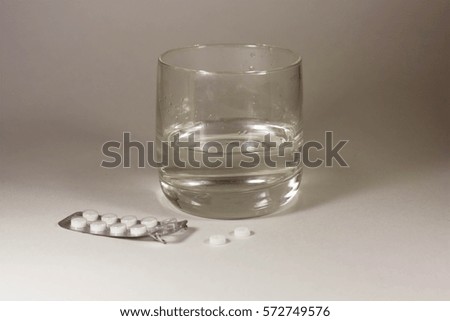 Tablets with a glass of water on a white background
