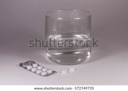 Tablets with a glass of water on a white background