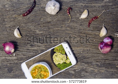 smartphone with picture of Omelette Cha-Om Sour Shrimp on old wooden floor