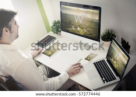 man working with devices with responsive theme website. All screen graphics are made up.