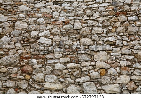 Antique medieval castle or fortress old rough white and brown rock stone layered wall paving texture background