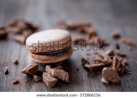 Chocolate and coffee macaroons or macarons on old dark brown wooden background