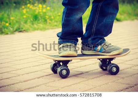 Closeup of skateboarder legs. Kid child riding skateboard outdoor. Active boy skateboarding on pavement sidewalk. Kid practicing outside. 