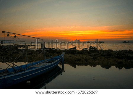 SILHOUETTE FISHERMAN BOAT AT ANCHORAGE IN LATE EVENING TIME AT SEASIDE , LIGHT REFLECTING ON WATER , ,BEAUTIFUL TWILIGHT SKY ABOVE ISLANDS BACKGROUND