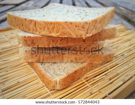 Rows of whole wheat bread on a wood floor.