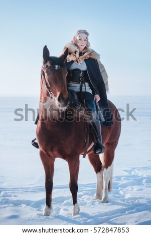 
Beautiful blonde girl on horseback. Photo shoot in the winter in the mountains. Snowy mountains. Model in a warm cloak. Fantasy illustration image.