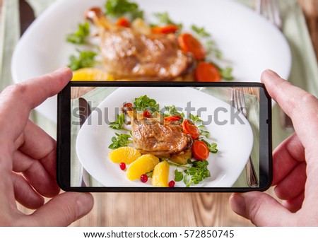 Smartphone photo of a main dish of duck leg and fresh vegetables setting.