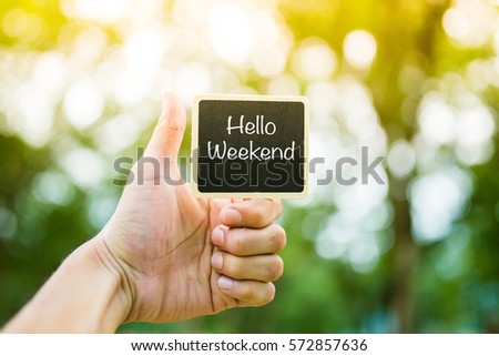 Hello Weekend word on Black Board with hand hold the board. Hands show Good Sign. Royalty-Free Stock Photo #572857636
