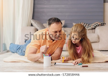 Cheerful old man painting with his granddaughter